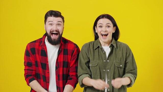 The guy and the girl are happy, the emotions of people. Young couple shouting cheers, good news, celebrating victory. Portrait on a yellow background in the studio