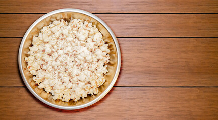 
Popcorn in round metal bowl on wooden table top view