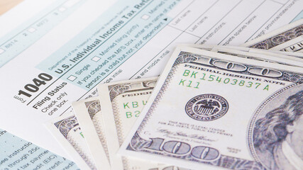 Tax day 1040 form and us hundred dollar bills.