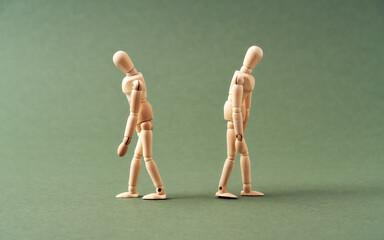 Two wooden figures walking away from each other on green background