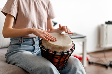 close-up female hands playing djembe indoors