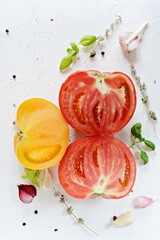 Ripe red and yellow tomatoes with garlic, basil, thyme and spices on a white background. Healthy eating concept.