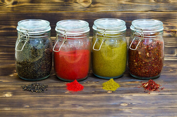 Assortment of assorted spices, black pepper, chili flakes, cardamom, paprika in glass jars on a...