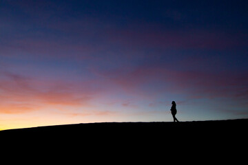 silhouette of a person standing on the top of a mountain