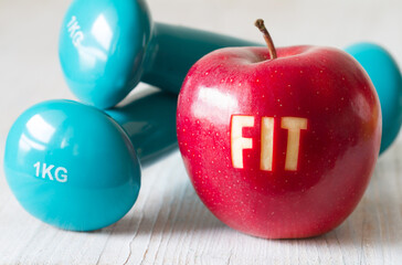 Red apple with word FIT and dumbbells, healthy diet and sport concept 