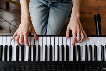 young woman playing piano at home. view from above