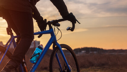 Cyclist riding his bike against sunset sky background.