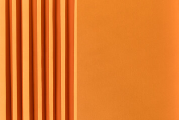 Abstract bright orange colored paper texture. Folded paper with harsh sun shadows, geometric shapes and lines. Minimalist background. Flat lay. Copy space.