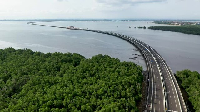 Cars driving along south Mandara Toll Road in Bali Indonesia above the Gulf of Benoa, Aerial dolly left shot