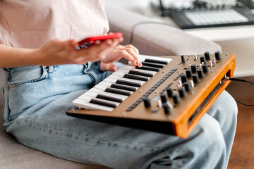 woman hands playing minilogue synthesizer using mobile app at home closeup