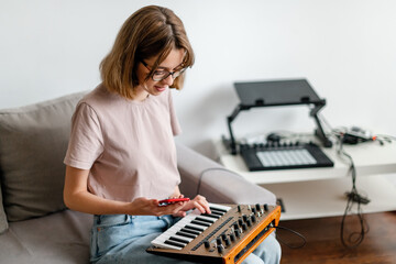woman hands playing minilogue synthesizer using mobile app at home
