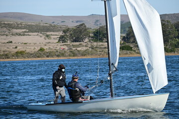 Naklejka premium Men adjusting their racing boat sail in a sunny day
