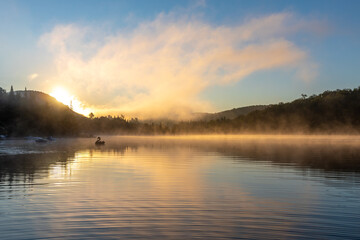 Fototapeta na wymiar vue large d'un cygne gonflable qui flotte sur un lac super calme lors d'un lever de soleil