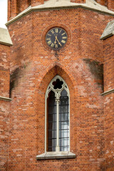 Fototapeta na wymiar Ornate window and clock on the wall of Church of St Matthew the Apostle, Rokiskis, Lithuania