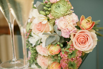 Wedding bouquet close up. Two glasses of champagne. Blur and selective focus. 