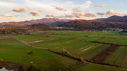 Spectacular aerial panorama of river flowing through fields at sunset.