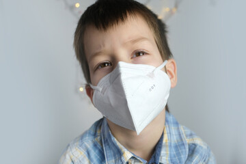small child, kid 7-8 years old in a white mask class FFP2, close-up face, medical concept, tired of...