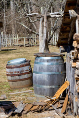 Rustic farmyard scene with old barrels and woodpile next to a woodshed.