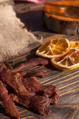 Organic dried chicken on a wooden stand, dried orange slices in the background. Jerky. Snacks. 
