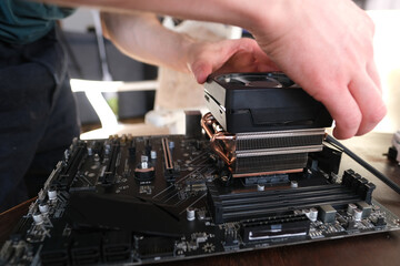 hands of young male master install cooler with copper heat pipes for the processor, other parts of...