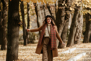 beautiful young woman in beret and coat walks in the autumn city
