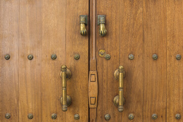 Obraz premium Detail of a studded, wooden door with iron doorknobs and hand knockers