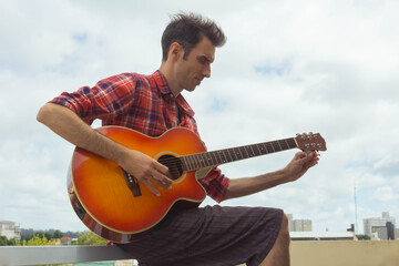 young man playing guitar on the balcony