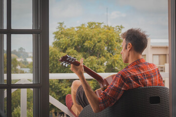 young man playing guitar on the balcony