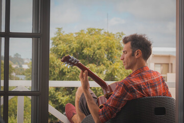 young man playing guitar on the balcony