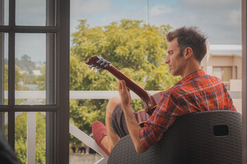 young man playing guitar on the balcony