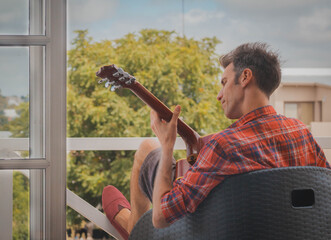 young man playing guitar on the balcony