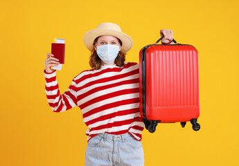 Cheerful young female passenger with passport and luggage in yellow studio