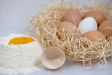 eggs in a nest and one is broken on a pile of flour