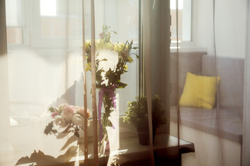 Spring flowers in vase at window home. Summer spring time, happy life concept. Breeze sways the curtains.
