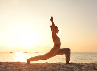 Fototapeta na wymiar Female practicing Crescent Lunge pose on sunset beach