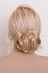 Female back with blonde hair and fashion hairstyle in beauty salon