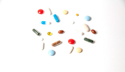 many pills of different shapes and different colors on a white background