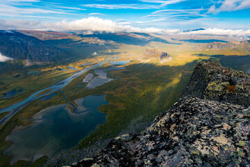 Beautiful, wild arctic valley viewed from mountain top in epic early morning light. Remote Rapa river valley from the top of Skierfe in Sarek national park in Swedish Lapland. Autumn colors.