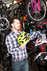Fototapeta na wymiar Young man selects a good helmet for cycling in a bike shop