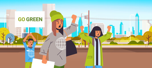 environmental activists holding posters go green save planet strike concept protesters campaigning to protect earth demonstrating against global warming portrait cityscape background horizontal