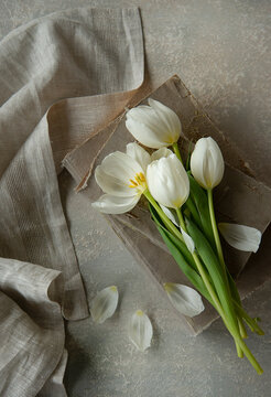 White tulip on an old book and a napkin on the side 
