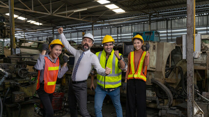 Group of factory workers or engineers with safety gears and hardhat express a great happiness after...