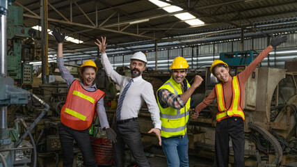 Group of factory workers or engineers with safety gears and hardhat express a great happiness after big business success or achievements