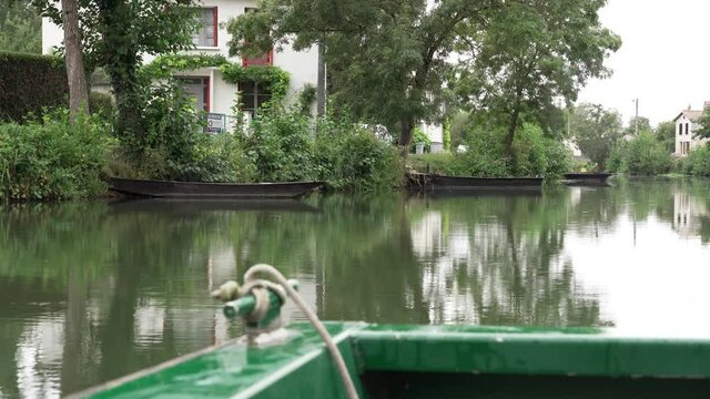 Sailing along the canal in the Maison du Marais Poitevin marsh in the South of France on a rainy day, view from the edge of the boat