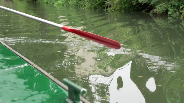 A close up of an ore paddling a boat along the canal in the Maison du Marais Poitevin marsh in the South of France
