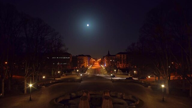 Timelapse of Munich at night, view from the Friedensengel Europaplatz at driving cars, stopping at red traffic lights, accelerating - stop and go under the full moon.