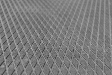 Abstract surface. Repeating rhombuses pattern. Dark gray porous texture. Selective focus.