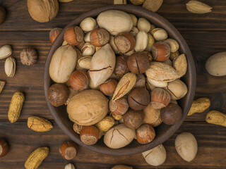 A bowl overflowing with walnut mixture on a wooden background.
