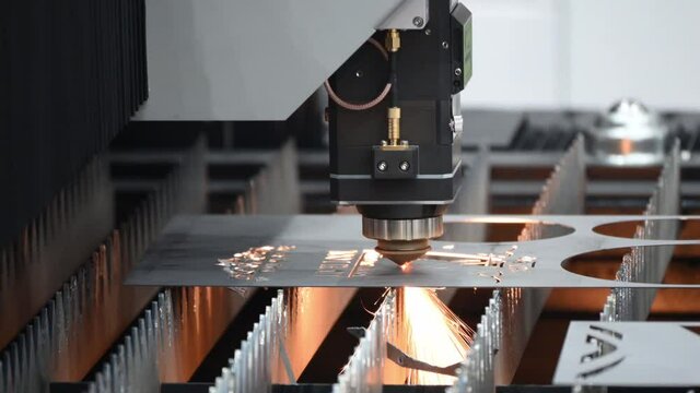 The fiber laser cutting machine engraving the metal plate with the sparkling light. The hi-technology sheet metal manufacturing process by laser cutting machine.