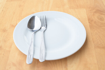 Empty plate and spoon fork on table.